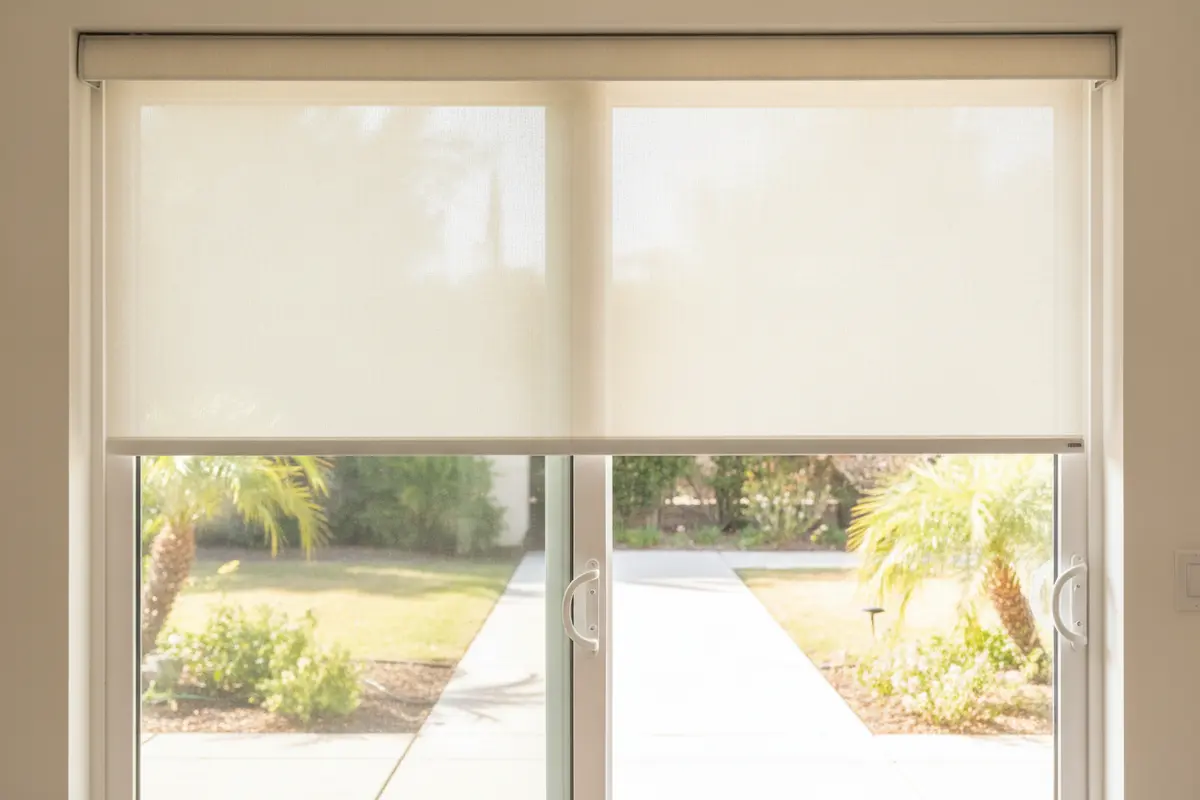 A motorized roller shade fitted above a sliding glass patio door