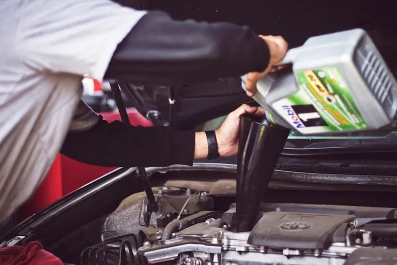 Mechanic inspecting a used car engine representing repair attempts and warranty claims