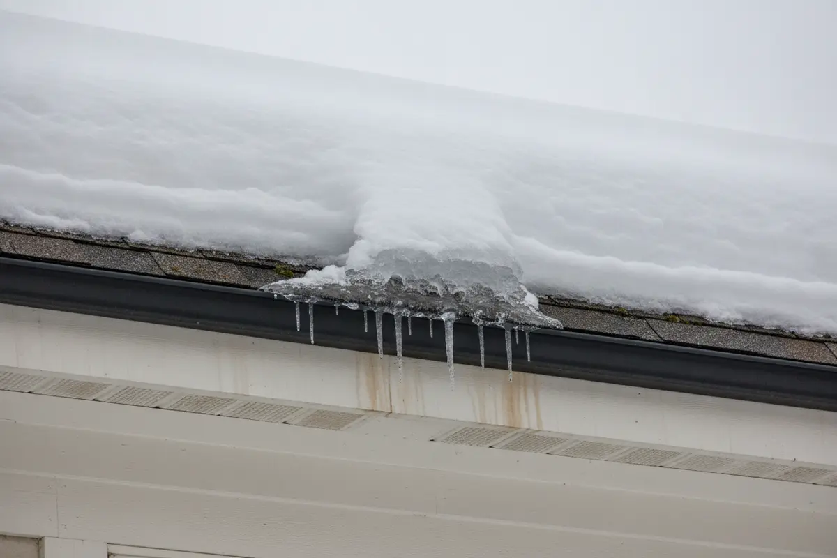 Snow and a modest ice ridge forming along a home's roof eave