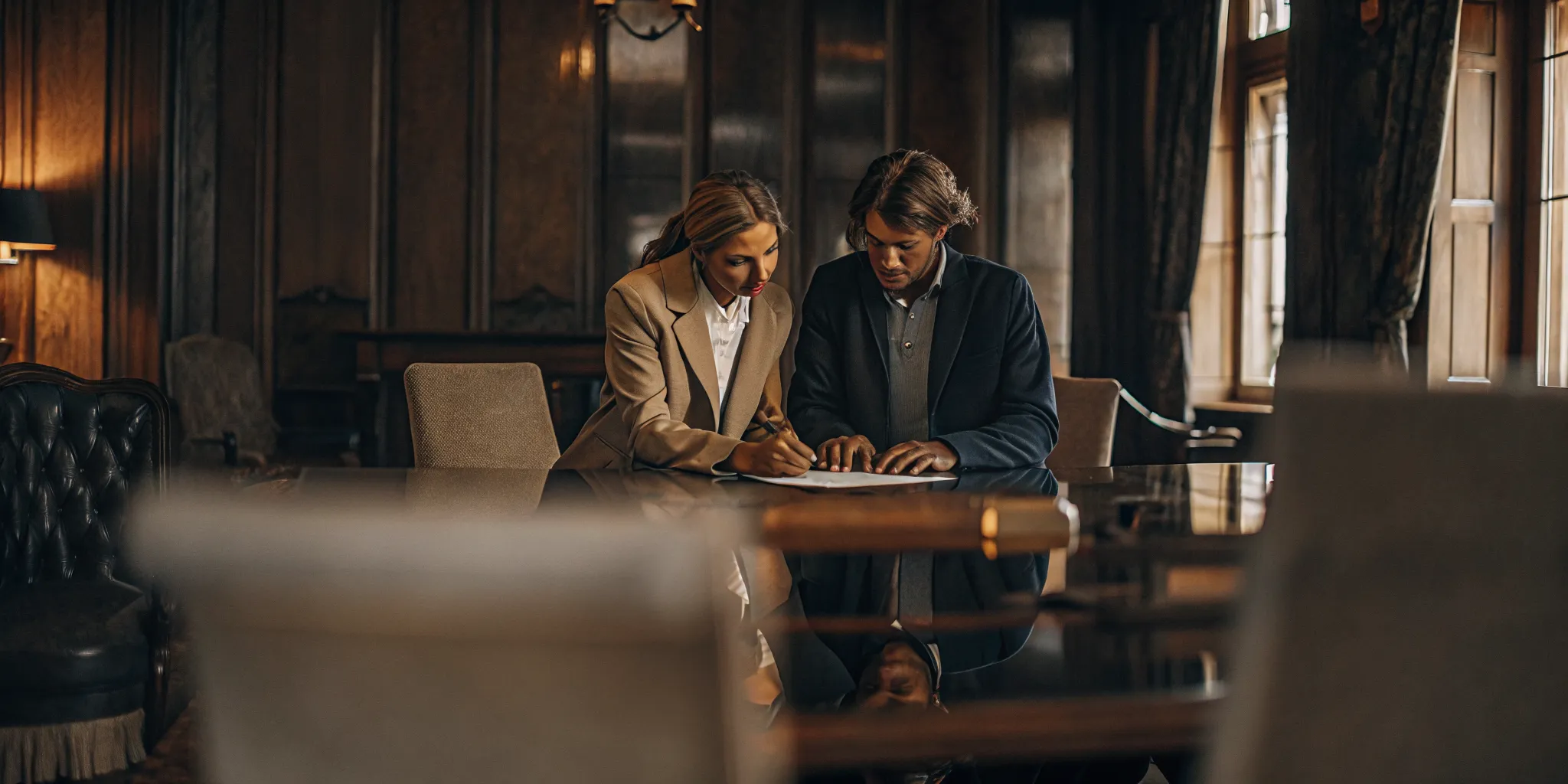 Couple signing mortgage closing documents with a loan officer in a professional office setting