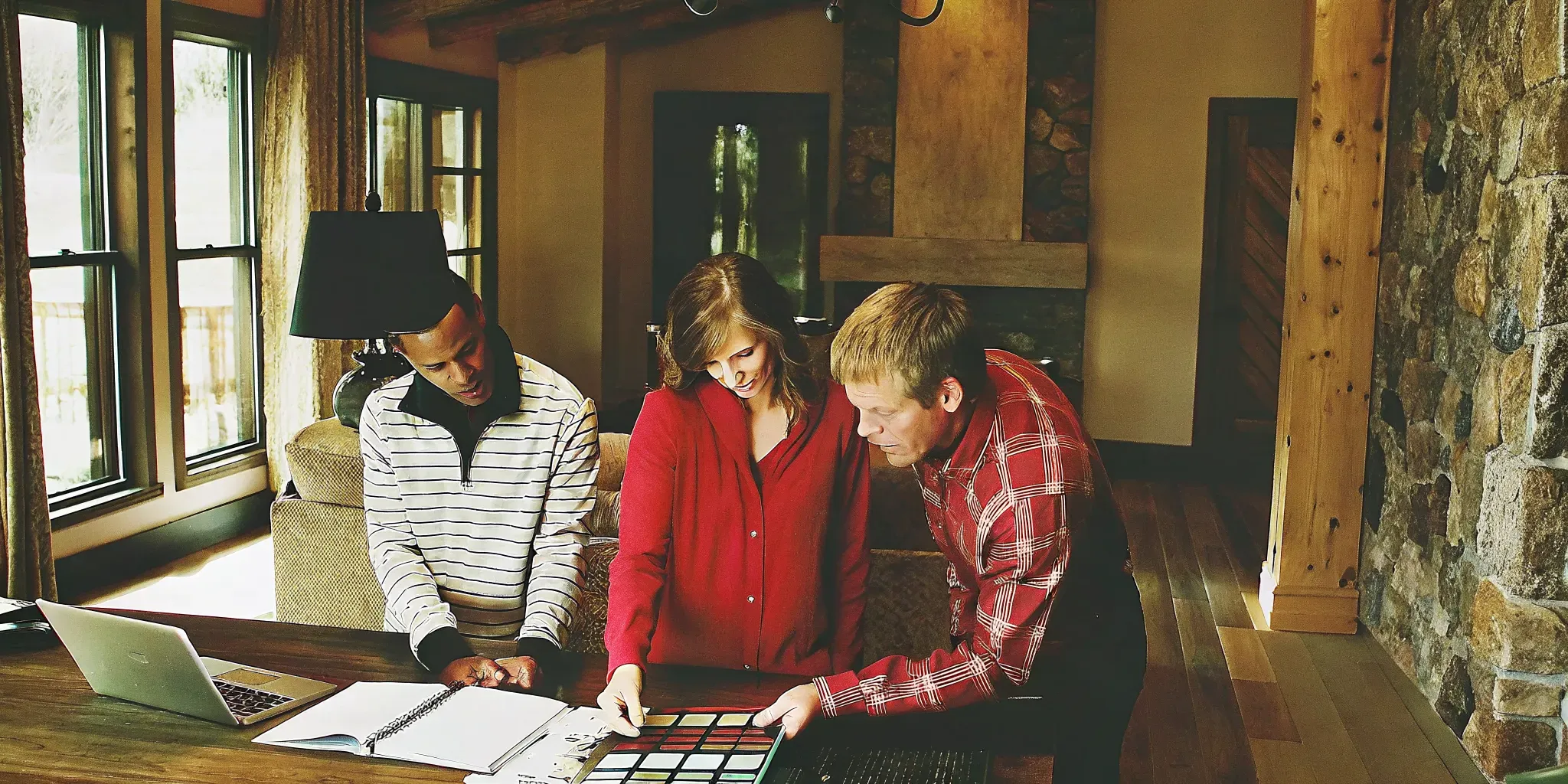 Homeowners reviewing interior finish selections with a designer in a sunlit Western Colorado design studio