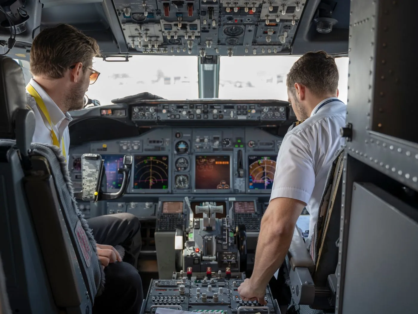 Two pilots in an airline cockpit reviewing flight controls