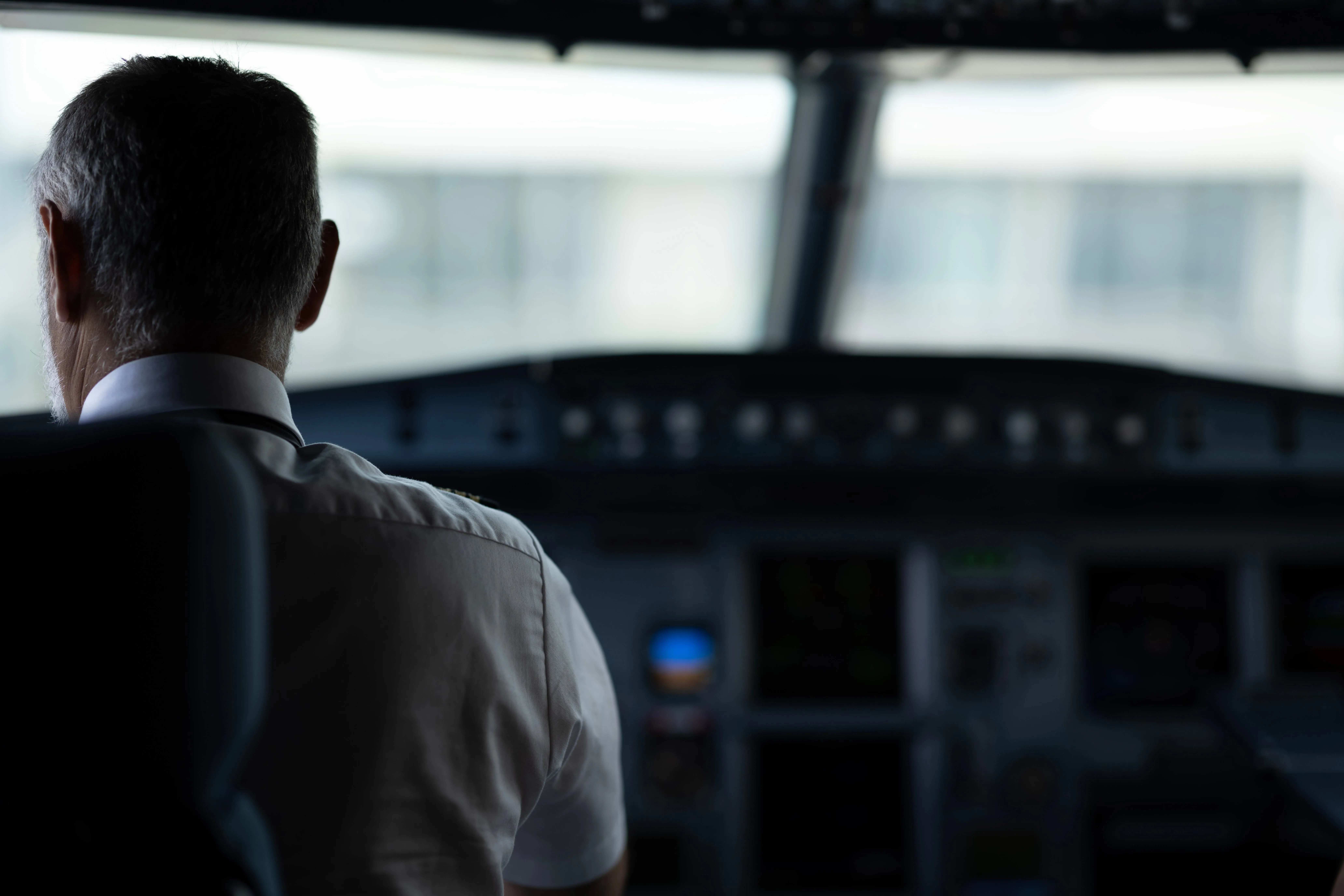 Professional airline pilot in uniform sitting in cockpit during flight