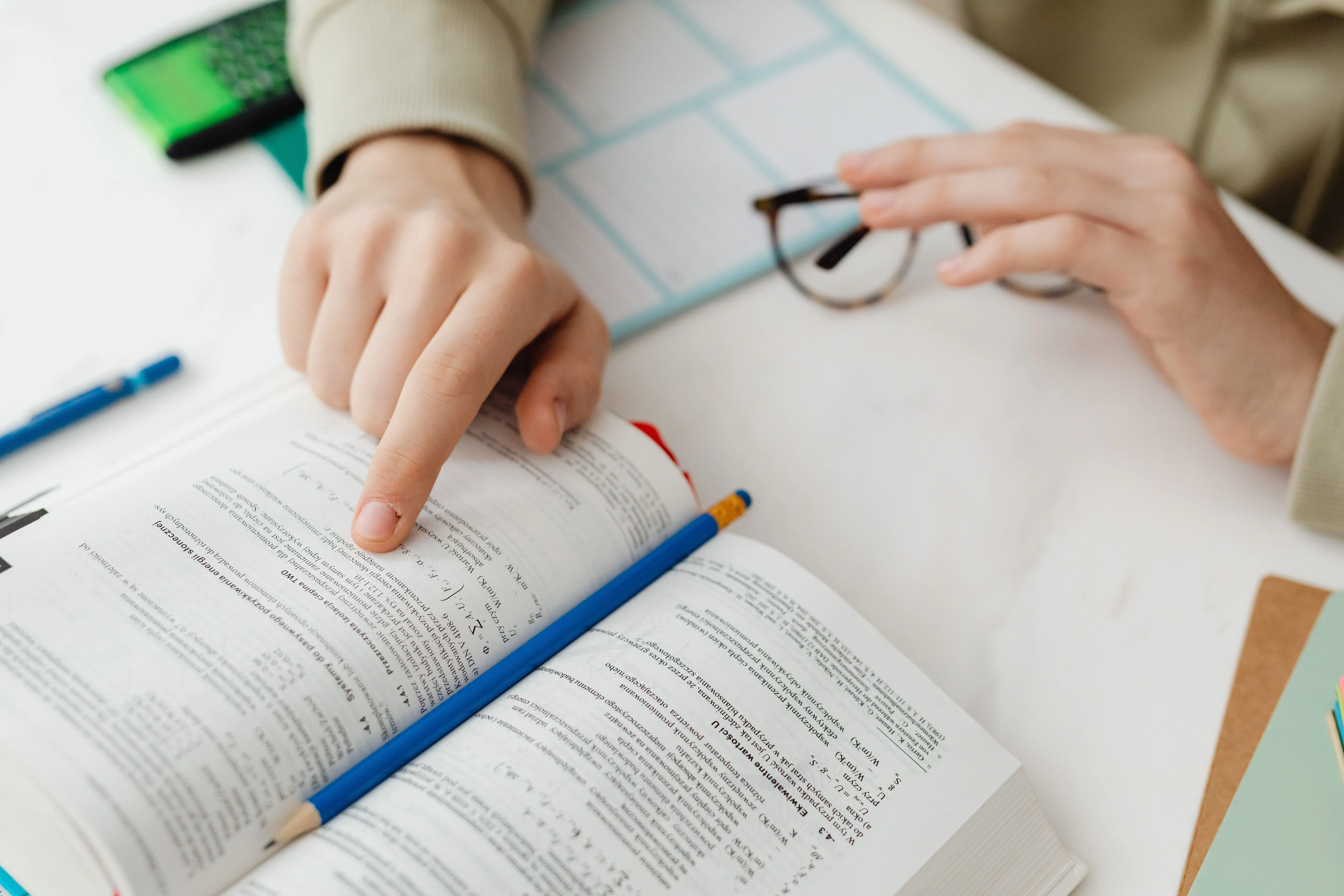 Student pilot studying with textbook and notes at a desk in preparation for aviation training