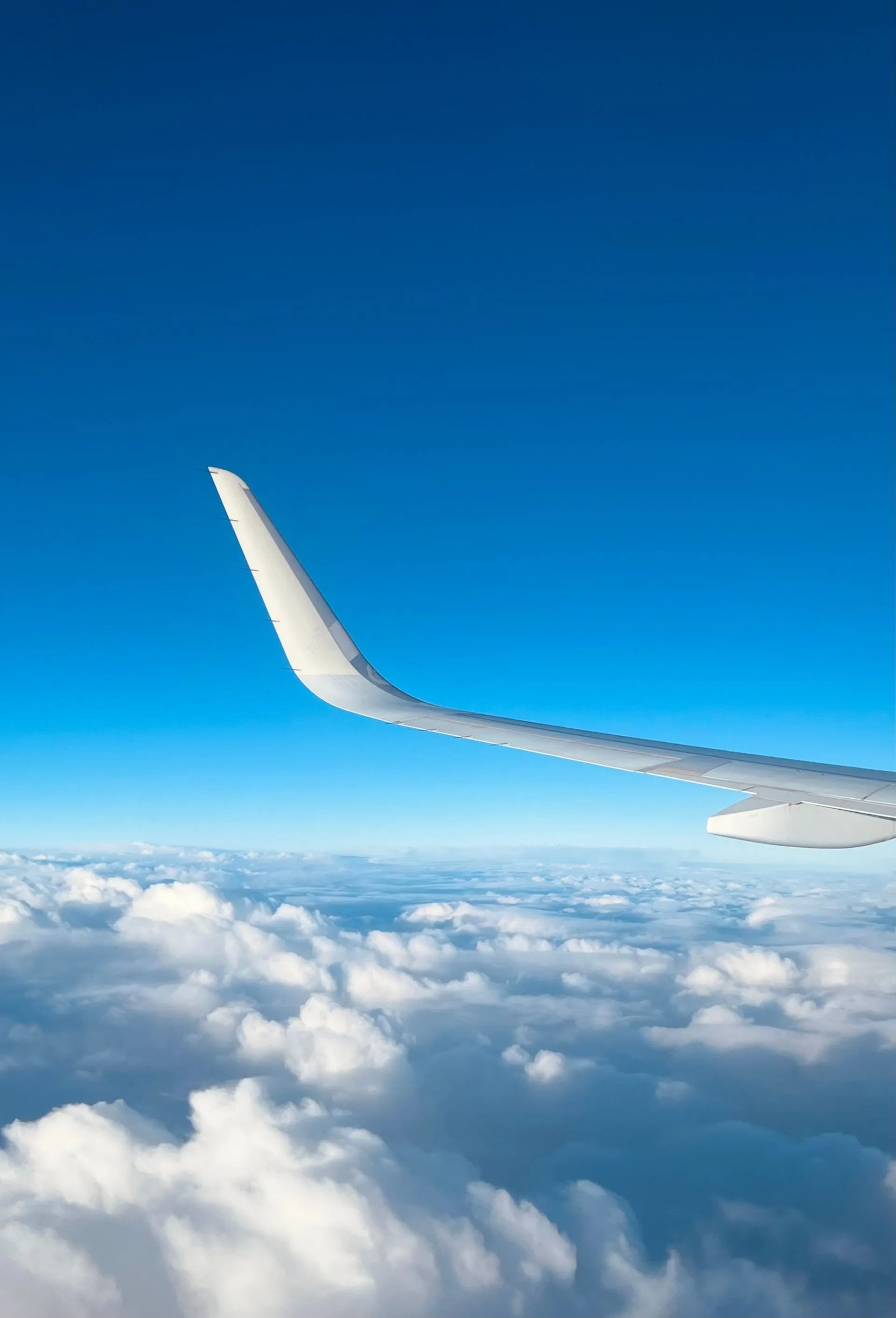 Aerial view of a commercial jet swept wing above clouds at cruising altitude