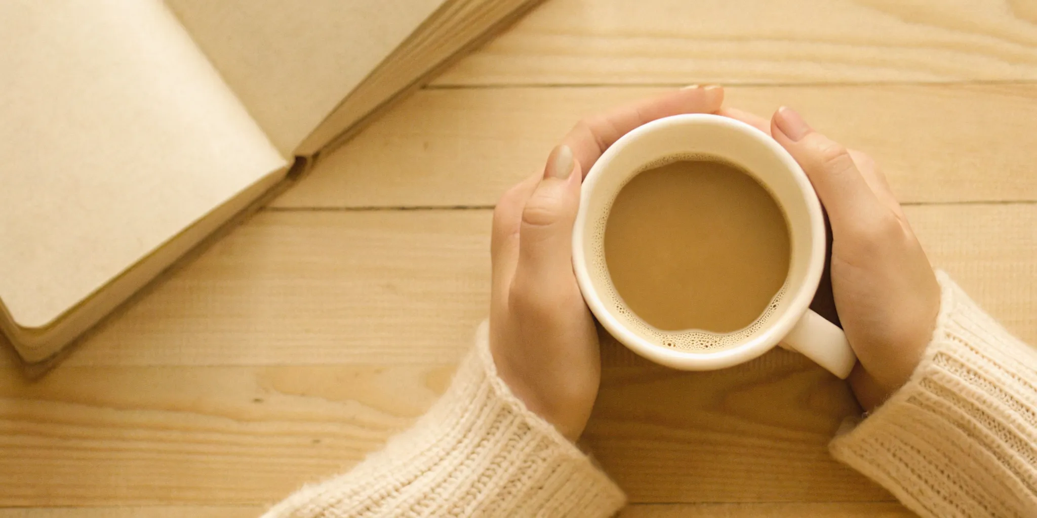 A person's hands holding a clean white ceramic mug filled with warm coffee, showcasing a balanced and gut-friendly morning routine.