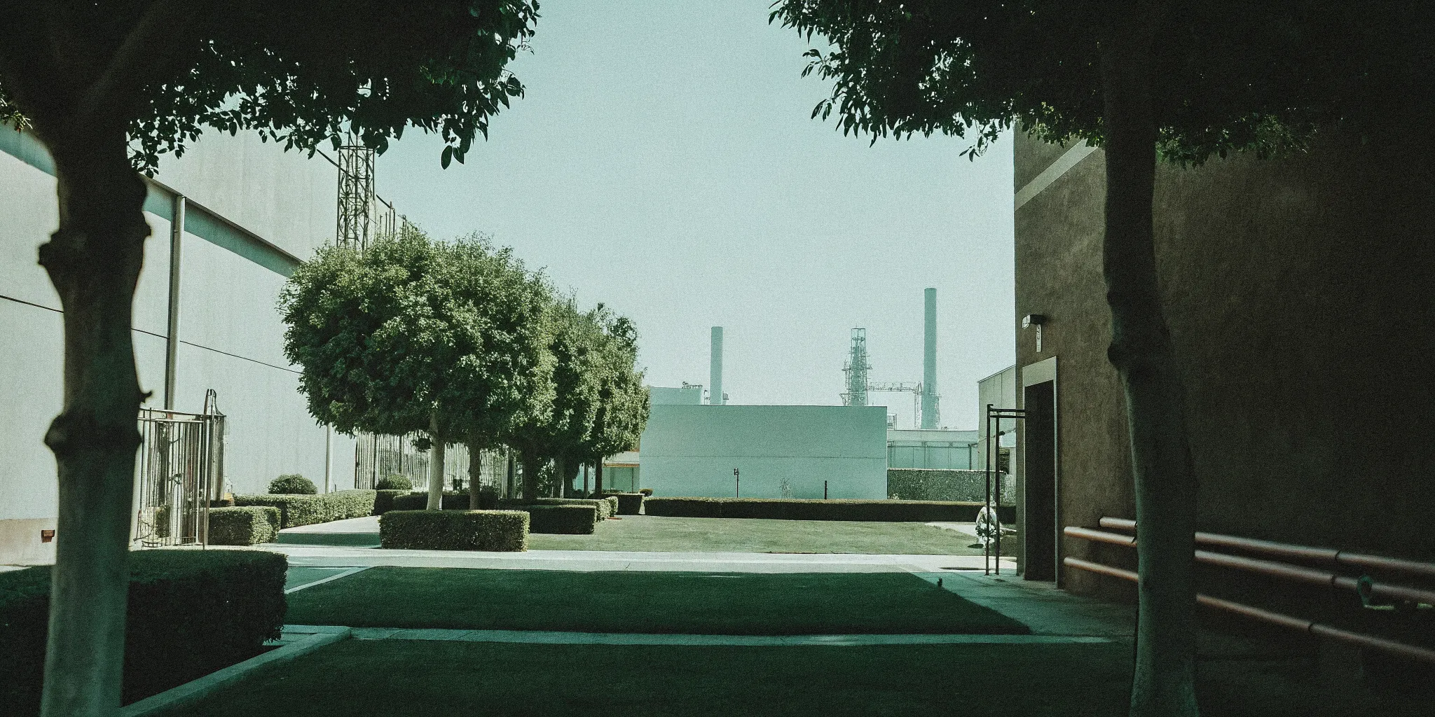 Professional manufacturing facility exterior with environmental compliance signage and green industrial landscape