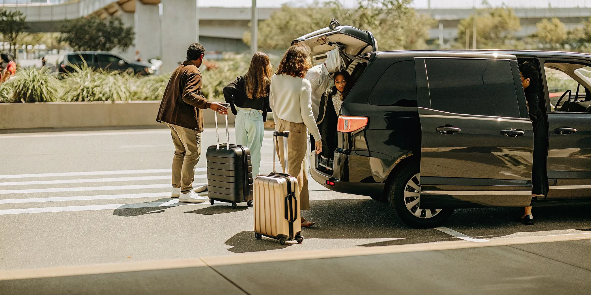 Group of travelers loading luggage into a private van at LAX for a coordinated airport transfer